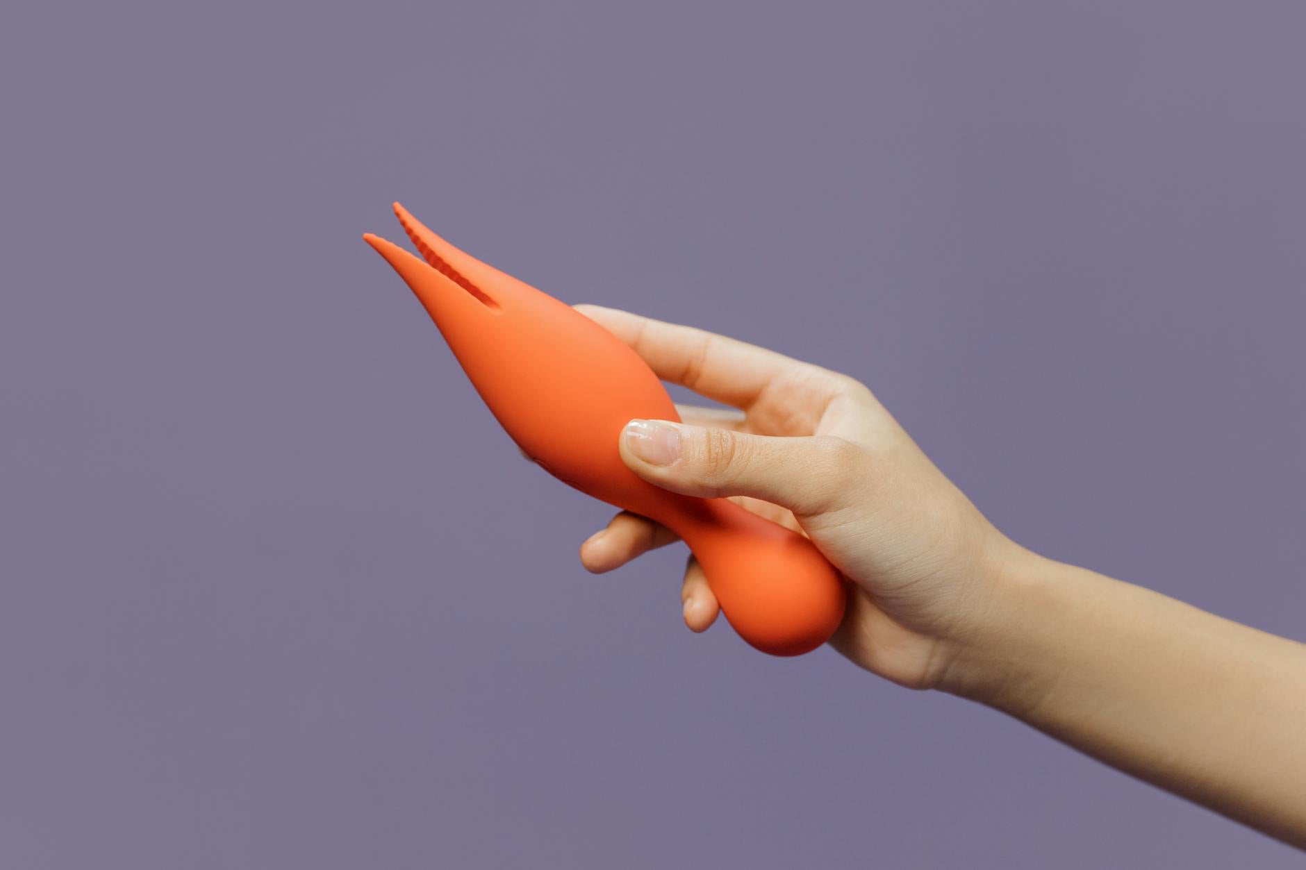 Close-up of a hand holding a lemon vibrator against a purple backdrop, showcasing modern sensuality
