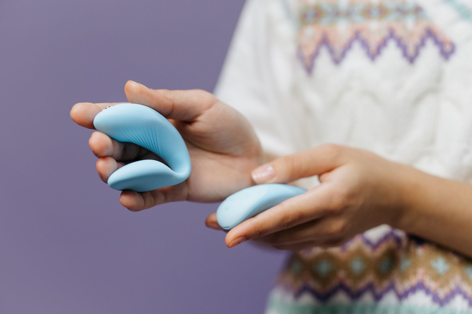 A person holding a sleek clitoral vibrator, representing air-suction technology for sensitive pleasure